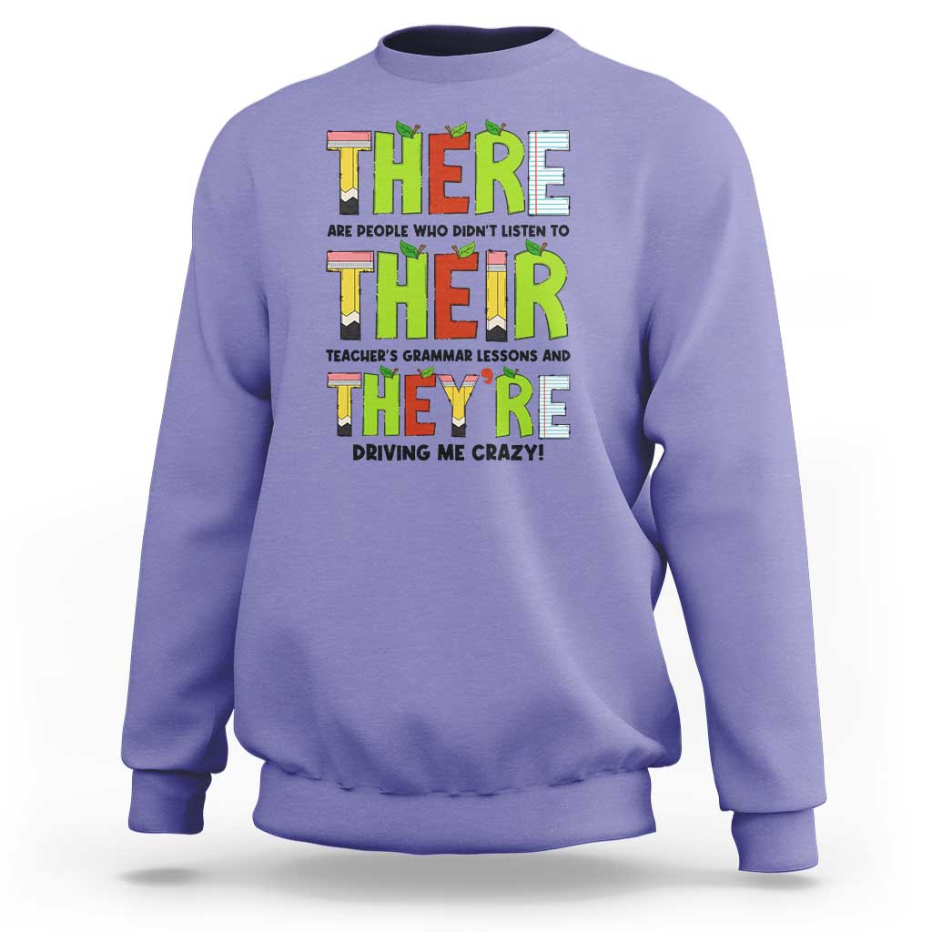 Purple sweatshirt with colorful “THERE/THEY’ grammar text graphic on the front, crew neck