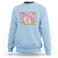 Light blue crewneck sweatshirt with teacher-themed graphic and pencil bow on chest