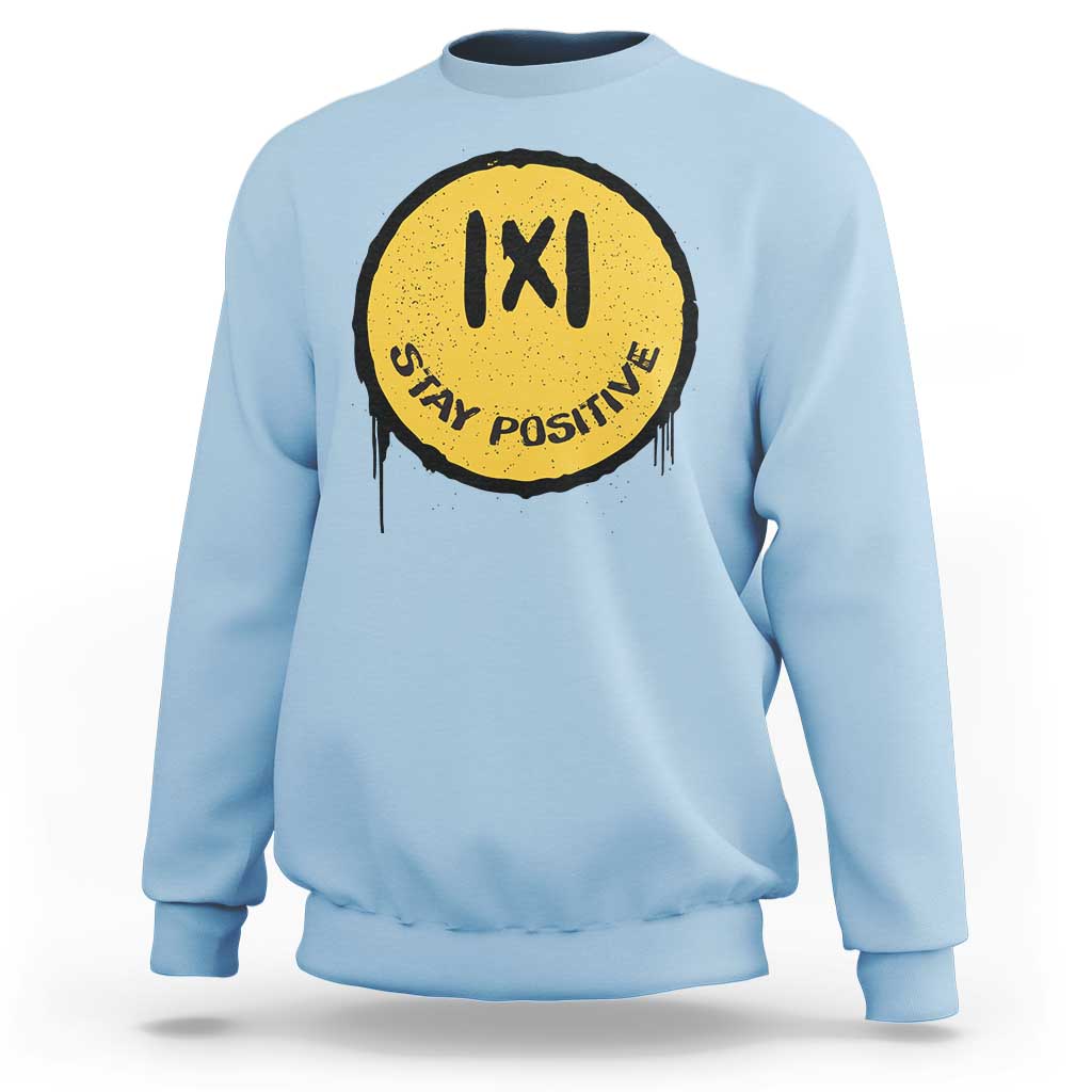Light blue crewneck sweatshirt with yellow “IXI” “Stay Positive” graphic on the chest