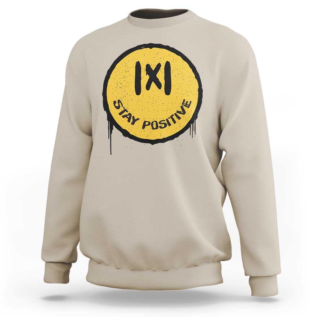 Sand crewneck sweatshirt with yellow “IXI” “Stay Positive” graphic on the chest