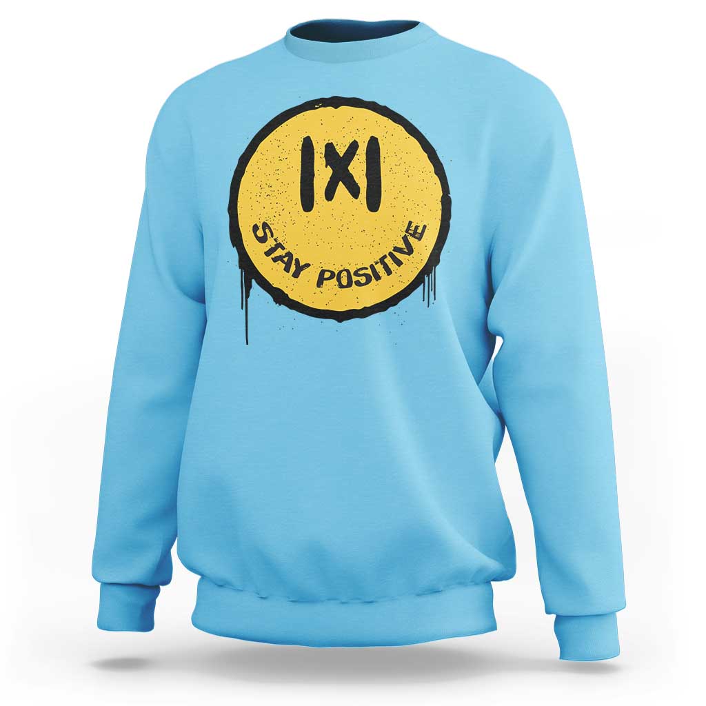Sky blue crewneck sweatshirt with yellow “IXI” “Stay Positive” graphic on the chest