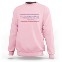 Light pink crewneck sweatshirt with Never Underestimate teacher graphic on chest