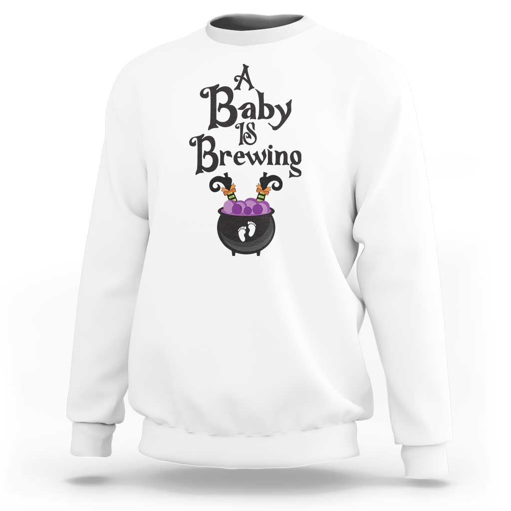 White crewneck maternity Halloween sweatshirt with “Baby is Brewing” cauldron print