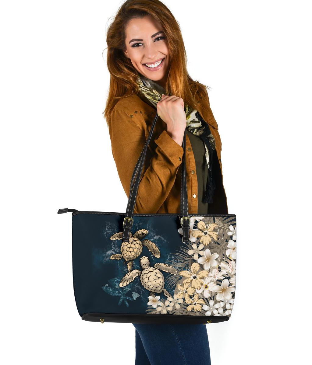 Navy tote bag with sea turtles and white/beige plumeria flowers, gold-toned hardware