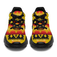 Pair of yellow chunky sneakers showing heel and toe, black laces, tribal pattern