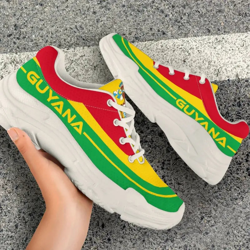 Side view of Guyana flag chunky sneakers; red toe, yellow center stripe, green accents, white sole