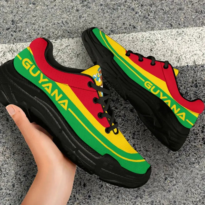 Close-up side angle of Guyana flag chunky sneakers; black sole, red and yellow panels with green stripe