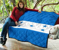 Blue and white Honduras star quilt draped across outdoor seating