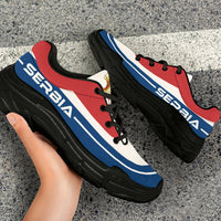 Chunky lace-up sneakers on feet: red white blue panels, black laces, black outsole