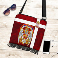 Red crossbody bag with Serbia crest, white panel stripe, black fringe along bottom edge