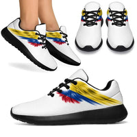 Mixed pair display: white sneakers with Colombia flag wings, black soles and laces