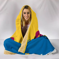 Hooded blanket laid out for wrapping, yellow hood and blue body with Swedish crest details