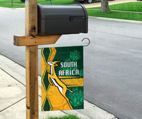 South Africa springbok flag hanging from stake, green and gold with “SOUTH AFRICA”