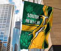 South Africa flag on building side, green and gold with springbok outline and “SOUTH AFRICA”