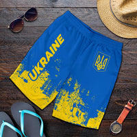 Folded men’s blue shorts with yellow smudge print, “UKRAINE” text and trident emblem