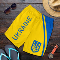 Flat-lay men's yellow Ukraine shorts with blue stripe, 'UKRAINE' lettering and trident logo