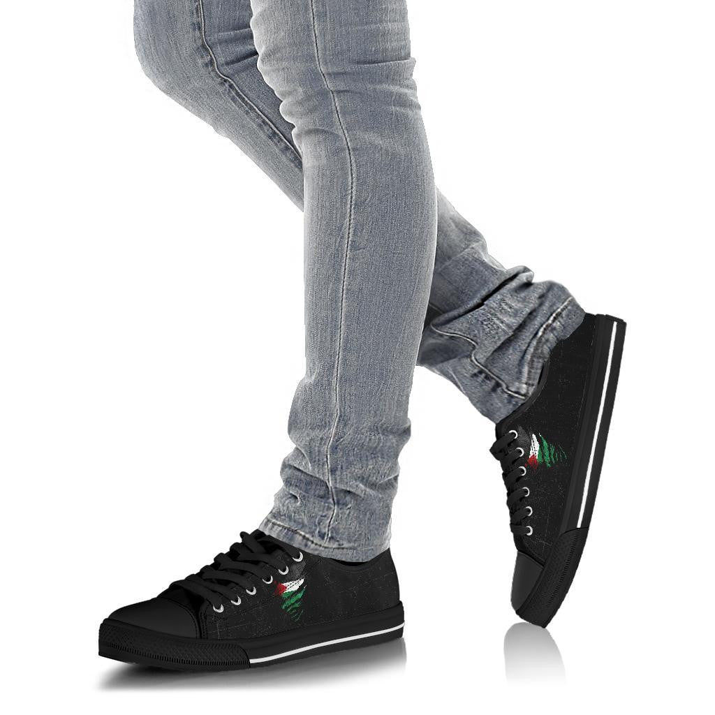Black low-top sneakers on feet with jeans, black laces, green/red graphic