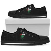Black low-top sneakers, black laces, green/red graphic on side, grunge style