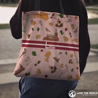 Latvia tote bag on shoulder, pink with colorful symbols and red 'Latvia' stripe; black handles.