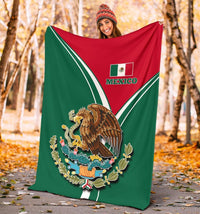 Person holding a Mexico pride blanket outdoors, red-and-green field with “MEXICO” logo and eagle