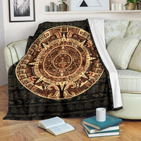 Dark woven blanket with large circular Mayan sun and tree of life pattern, draped over sofa