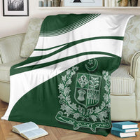 Green-and-white Pakistan coat of arms blanket draped on sofa, central emblem visible