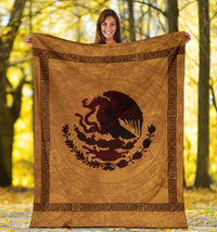 Gold throw blanket with dark red coat-of-arms bird emblem and ornate border