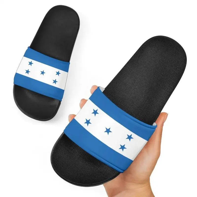 Close-up of Honduras flag slide sandals on textured black footbeds with blue-and-white star strap