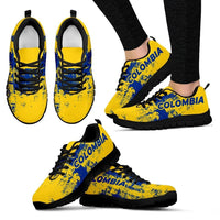 Pair of yellow lace-up sneakers with blue “COLOMBIA” logo, black sole