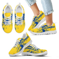 Yellow lace-up sneakers with blue “COLOMBIA” print, white sole on light denim