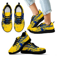 Yellow lace-up sneakers with blue “COLOMBIA” print, black sole on light denim
