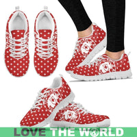 Red Swiss-cross sneakers with white laces, worn with black pants; white sole