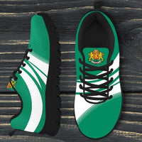 Side-by-side view of green/white sneakers with crest at tongue and black laces