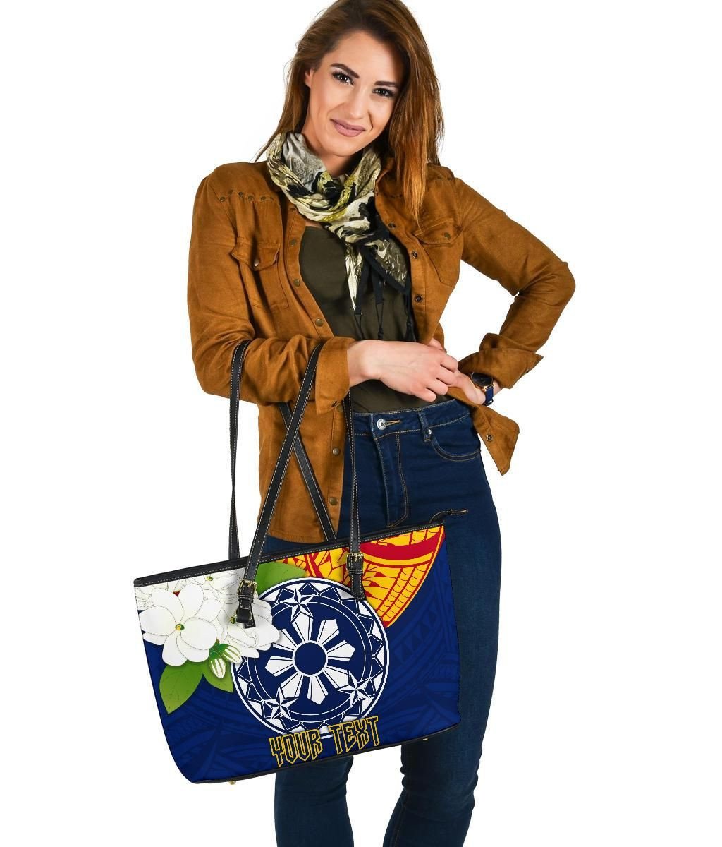 Blue tote carried low with wheel graphic, floral patch, black straps, top zipper