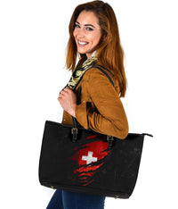 Black leather tote bag with red Swiss cross print, zip closure and reinforced handle straps