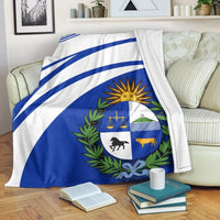 Blue-and-white blanket with Uruguay coat of arms in center, stripes across the fabric.