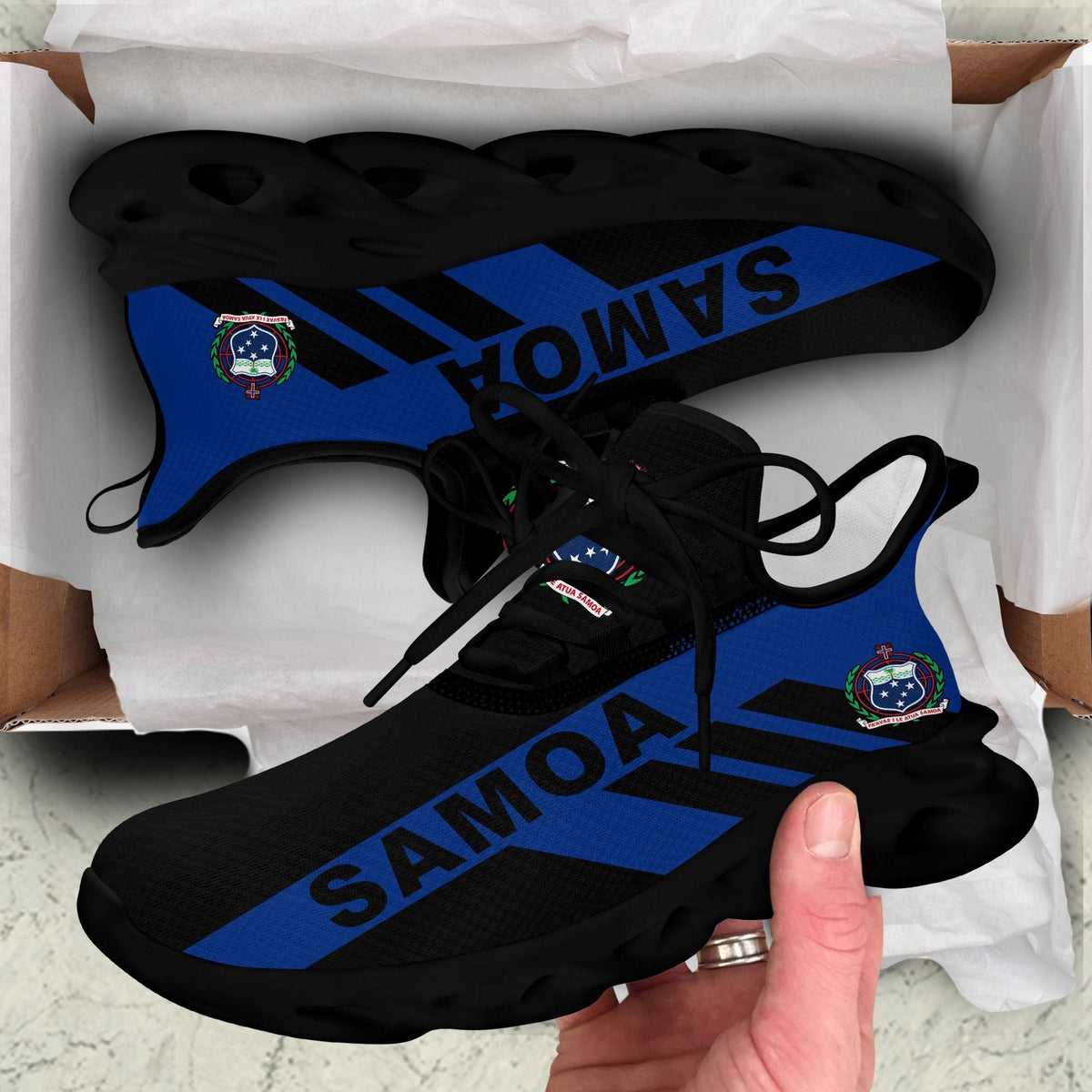 Black clunky sneakers with blue SAMOA stripe and dark ridged sole in box
