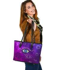 Purple small leather tote with evil eye graphic, black top handles and zipper pull