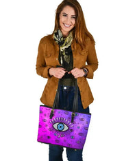 Pink leather tote featuring large blue evil eye emblem, black top straps and zipper