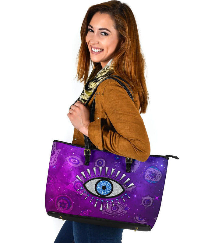Purple evil eye leather tote, black straps, rectangular shape in side view