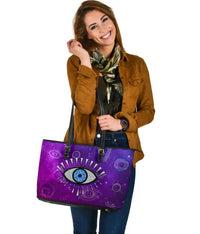 Purple leather tote with evil eye graphic and black handles, three-quarter view
