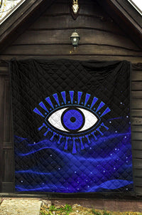 Quilt laid flat with black top and blue lower section, featuring a blue evil eye