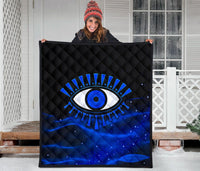 Black and blue quilt held up, showing large blue evil eye motif and starry speckles