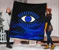 Blue quilt with black diamond quilting and bold evil eye graphic in blue/white