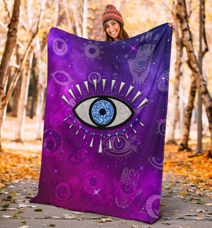 Purple throw blanket with central evil eye graphic and surrounding space symbols.