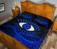 Black quilt with blue evil eye design, geometric rays, and diamond quilted pattern