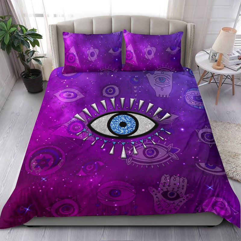 Purple bedding set on bed with two pillows featuring blue evil eye center design