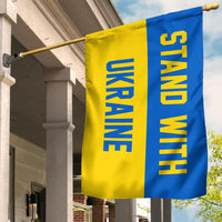 Blue-yellow striped flag with 'STAND WITH UKRAINE' lettering on house pole