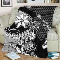 Black Hawaiian blanket draped over sofa, featuring white flower and tribal patterns