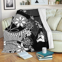 Black Hawaiian blanket with white tiki face, floral, and geometric zigzag details